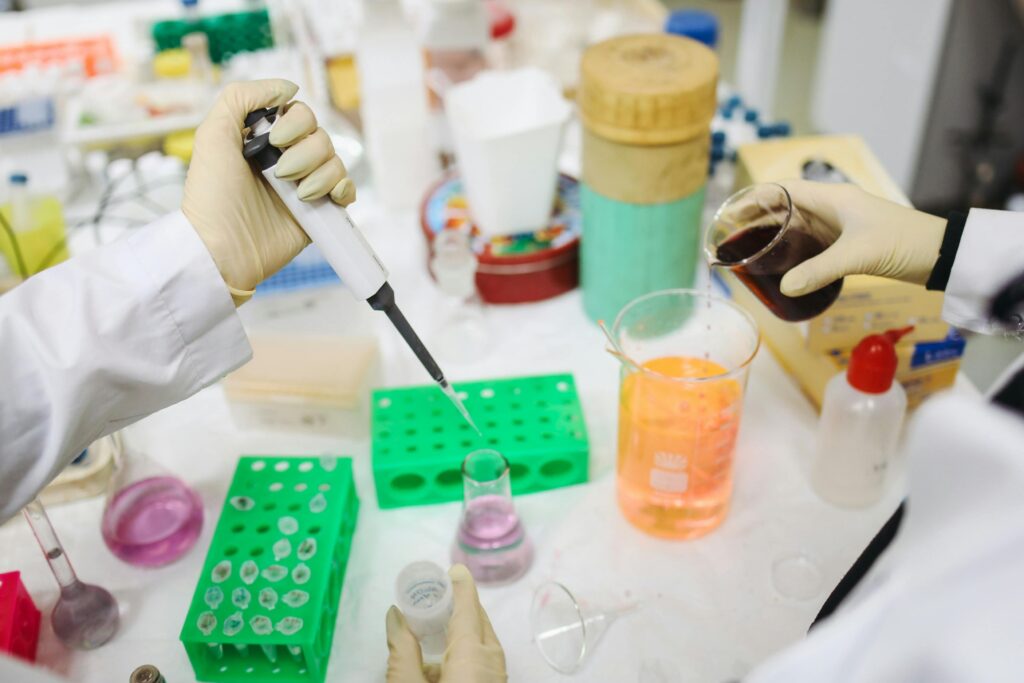 Close-up of lab researchers handling liquid samples and pipetting into test tubes, demonstrating the experimental processes behind precision medicine research.