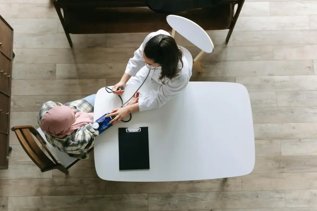 Doctor measuring blood pressure of a patient wearing a headscarf during a cardiology consultation.