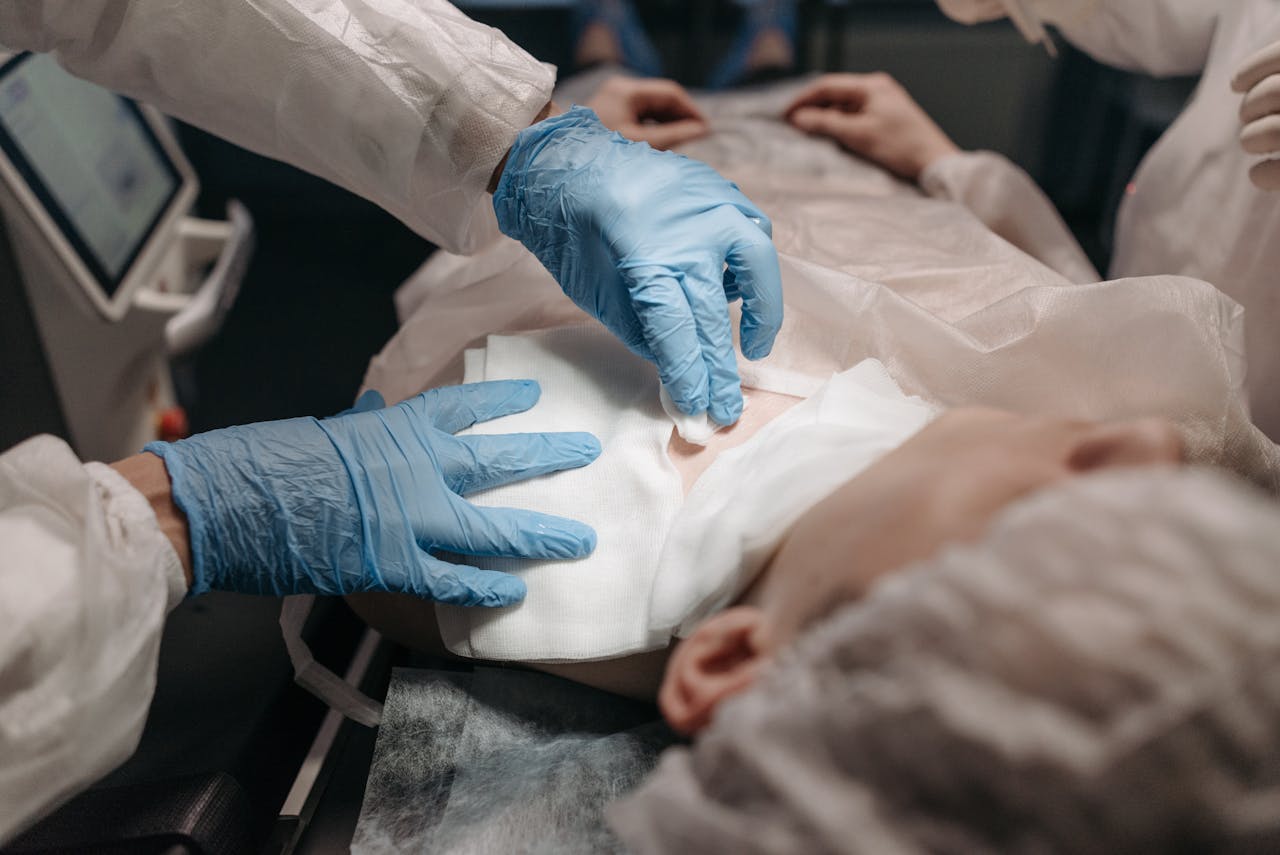 Close-up of general surgeons' gloved hands dressing a surgical site on a patient in an operating room.