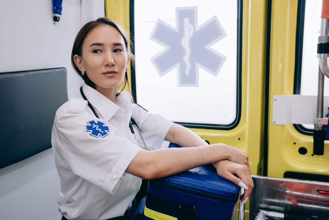 Emergency medical technician sitting inside an ambulance with a stethoscope around her neck.