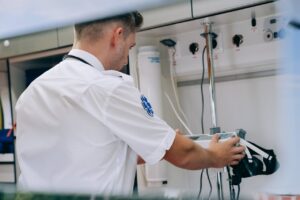 Paramedic adjusting emergency medical equipment inside an ambulance.