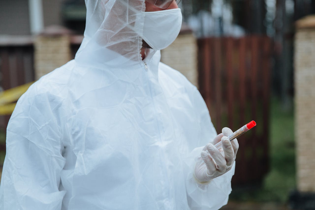 Epidemiologist in protective gear holding a blood sample for disease investigation.