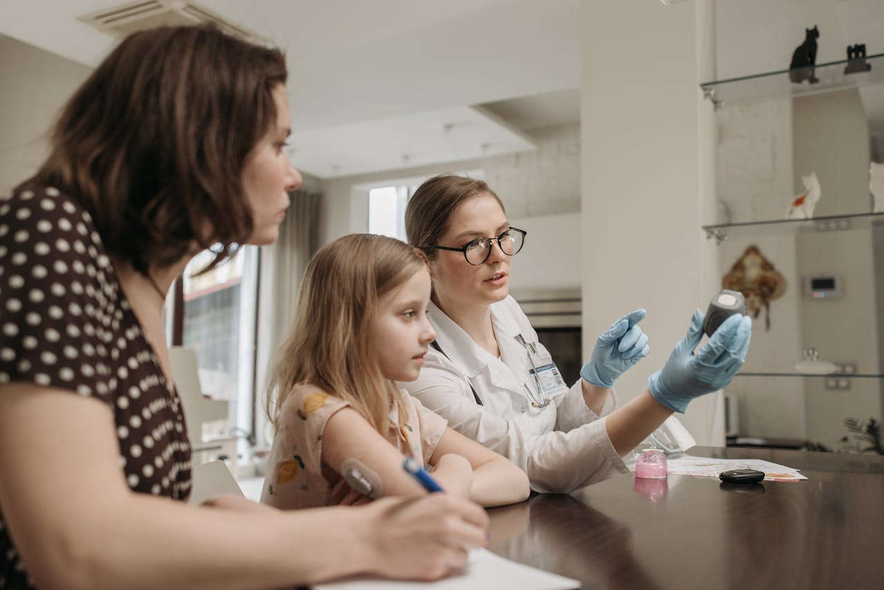 Family medicine doctor discussing a medical device with a mother and her daughter during consultation.
