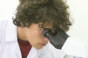 A haematologist using a microscope in a laboratory, a common setting in careers in haematology.