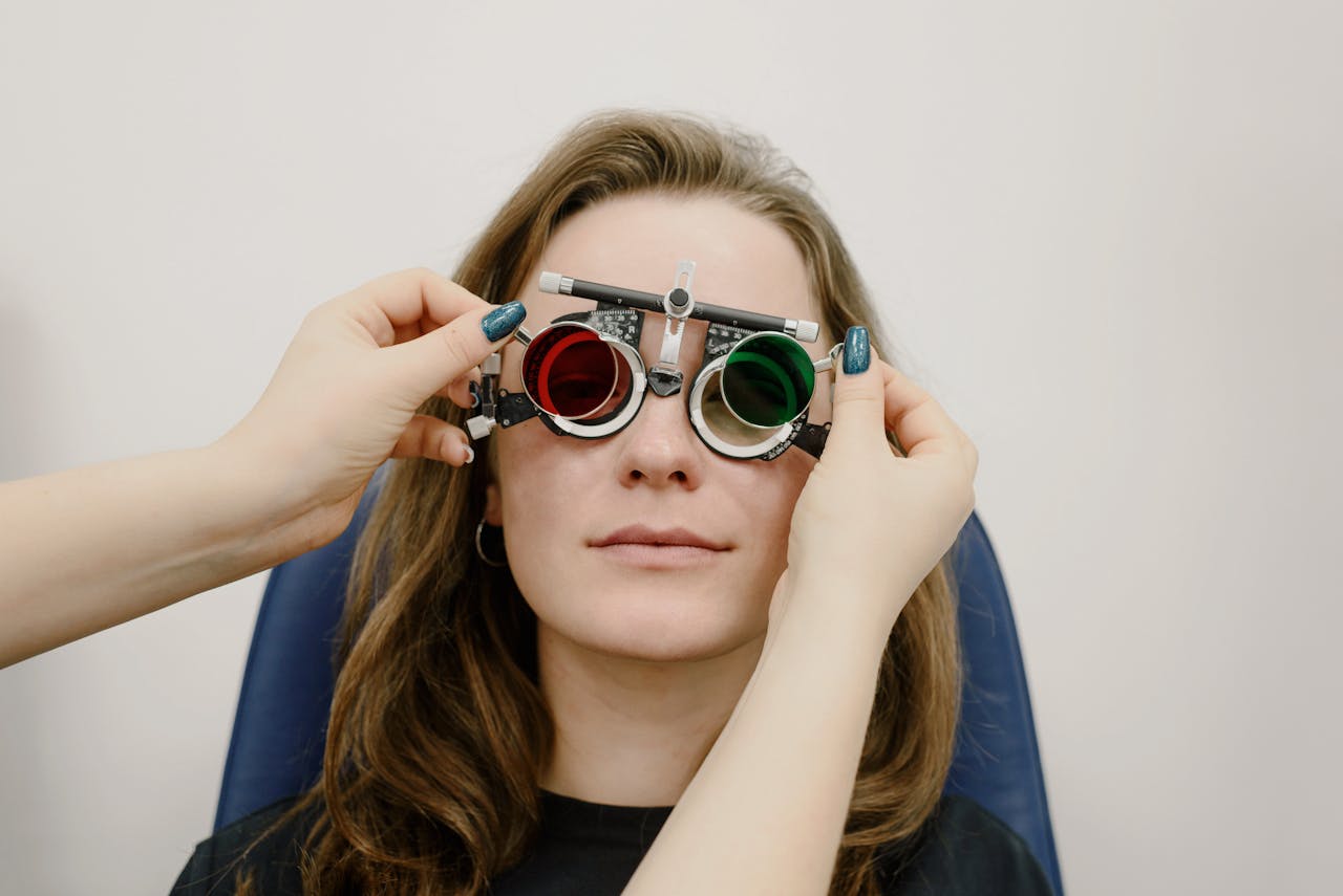 Female patient undergoing vision test with red-green lenses at an ophthalmology clinic.