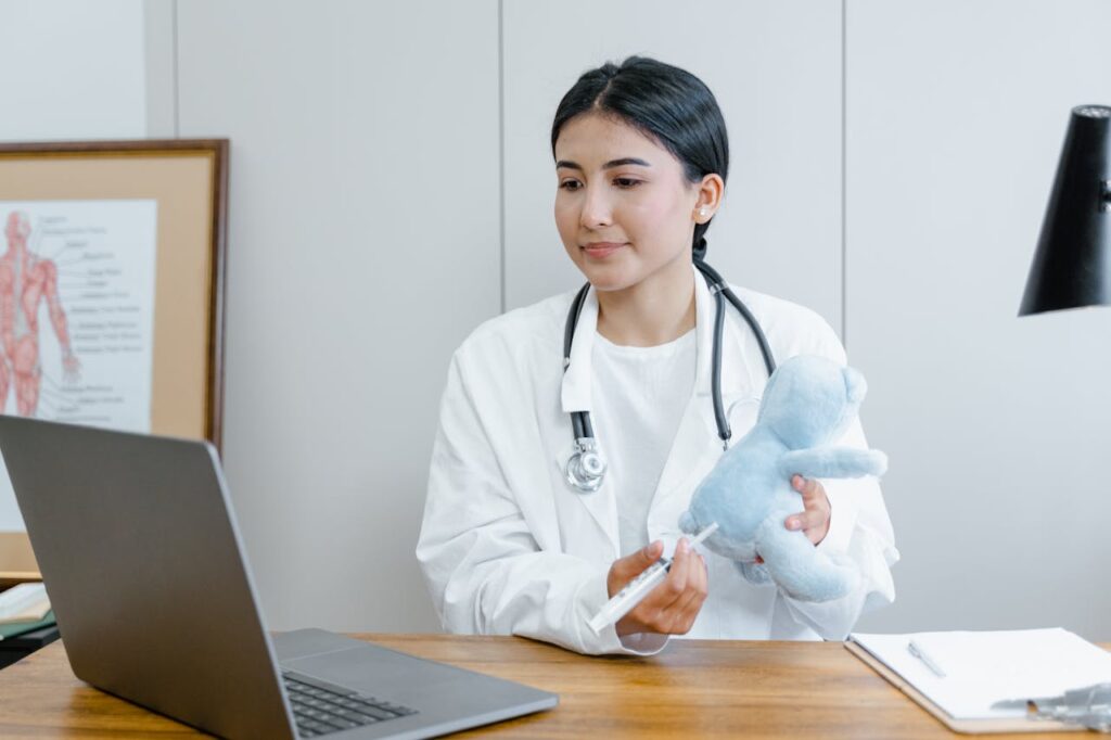 Paediatrician demonstrating vaccination technique with a soft toy during virtual consultation.