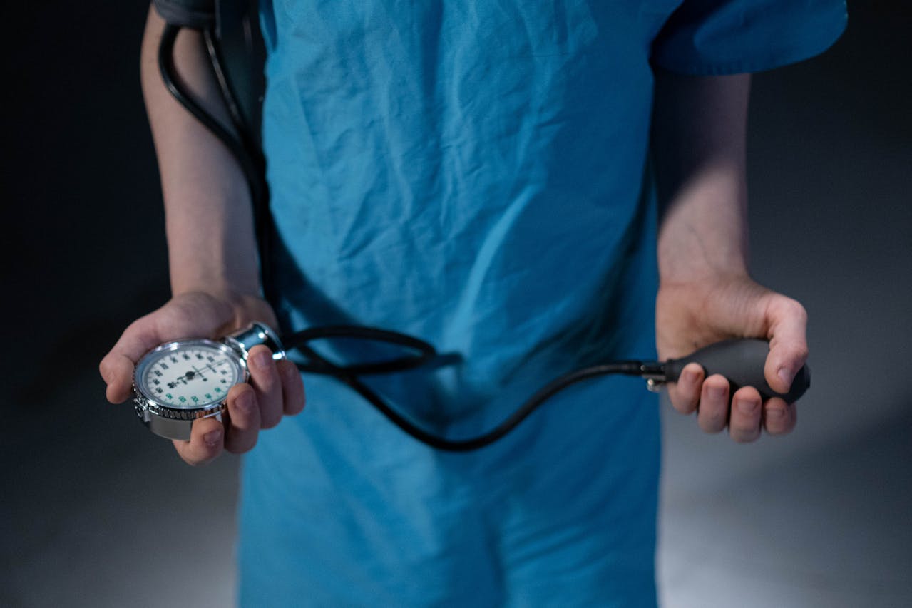 Medical professional in scrubs holding a sphygmomanometer to measure blood pressure.