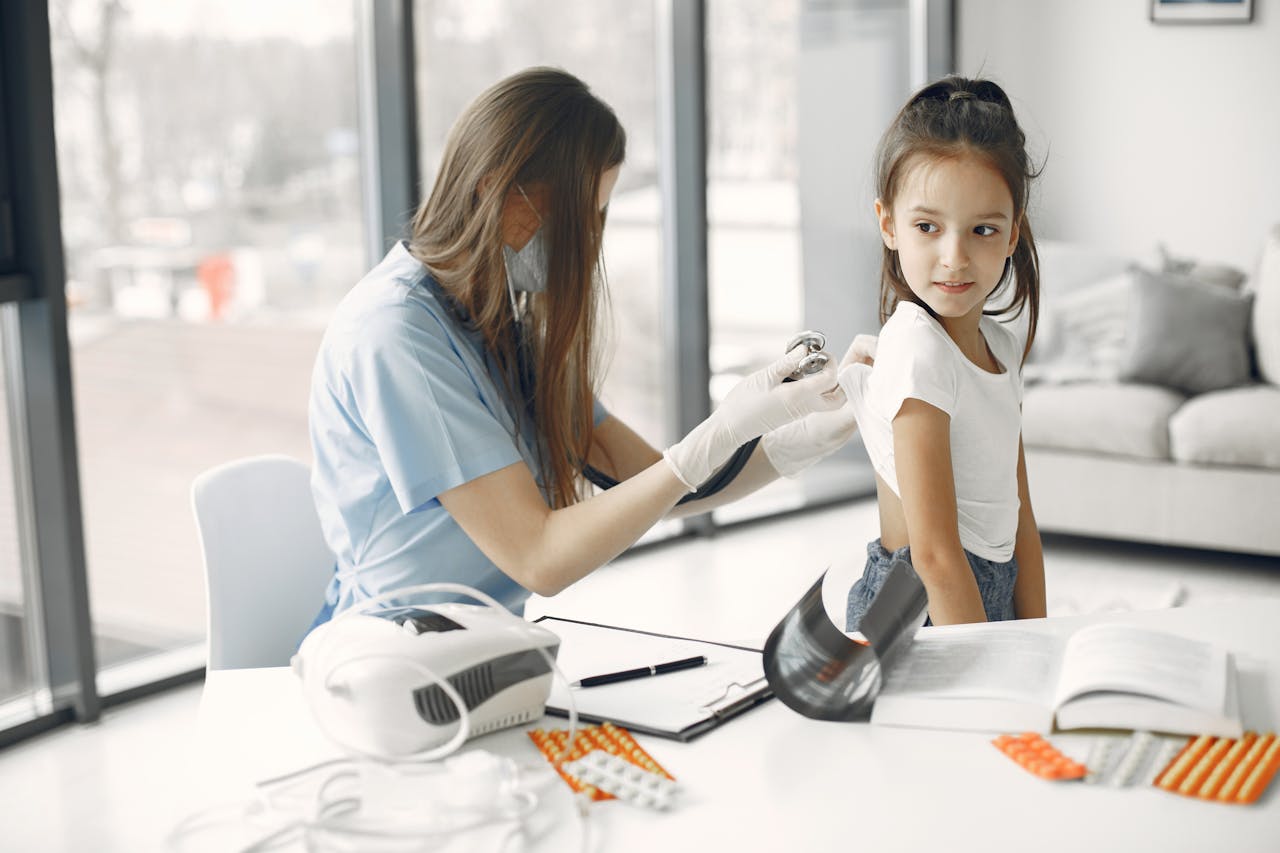 Paediatric nurse using a stethoscope to check a young girl's heartbeat at a medical consultation.