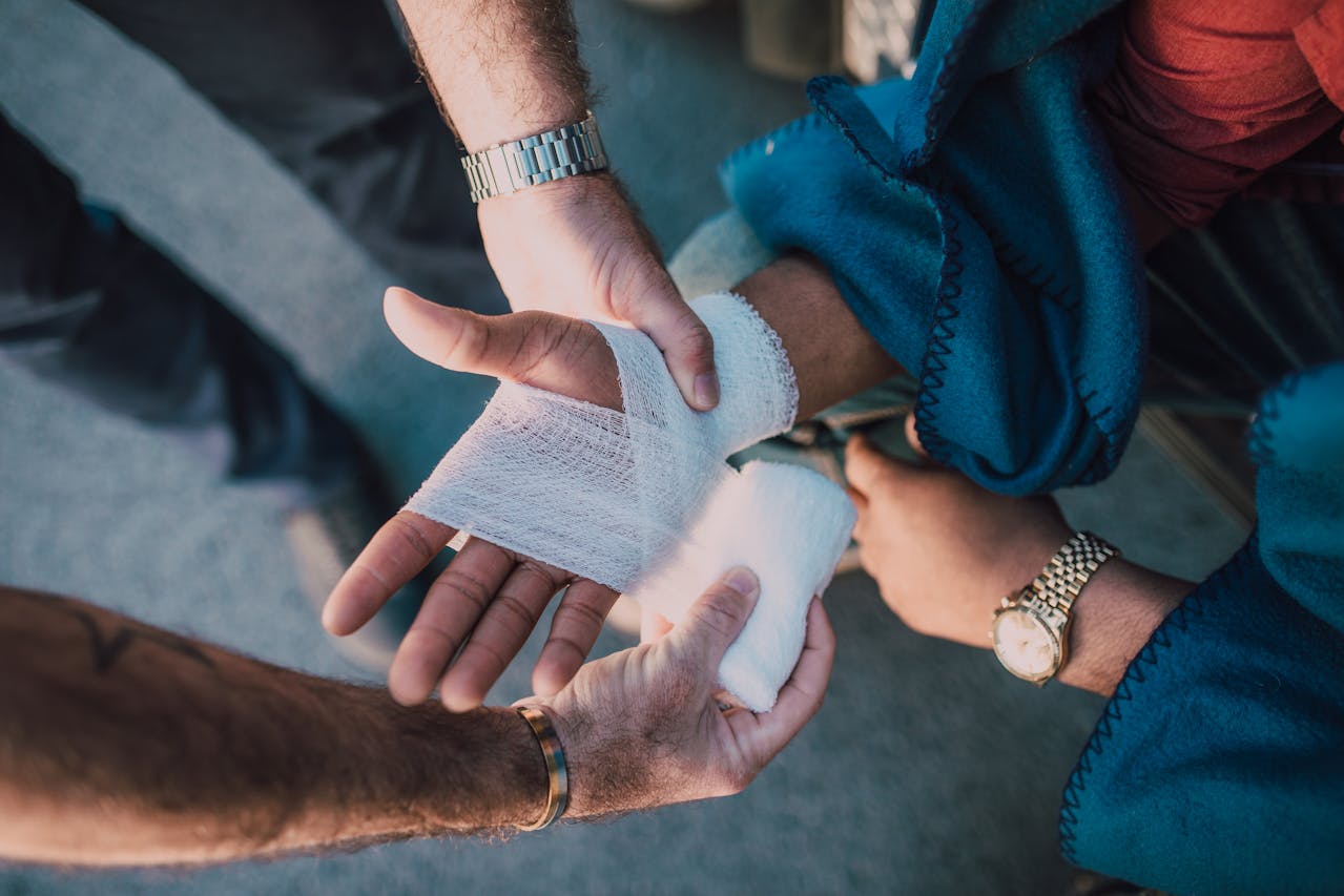 Emergency medicine doctor bandaging a patient’s hand during first aid treatment.