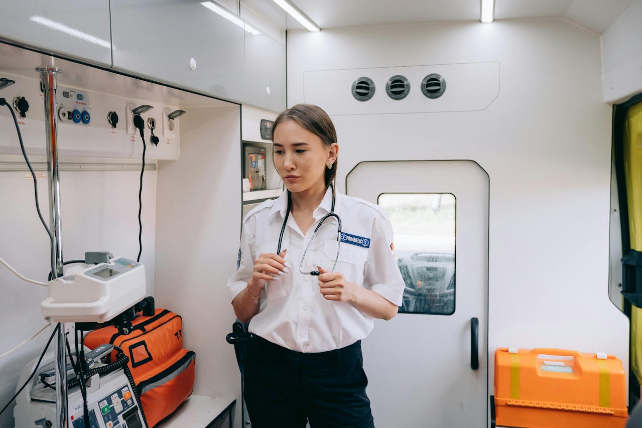 Paramedic standing inside an ambulance next to medical equipment and supplies.