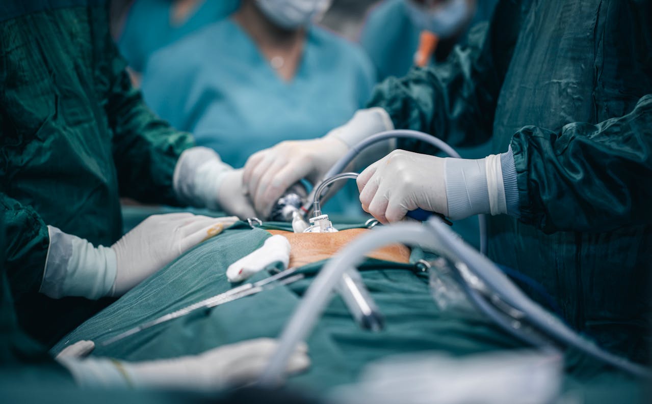 A close-up view of general surgeons operating on a patient in a hospital, surrounded by medical instruments and monitoring equipment.
