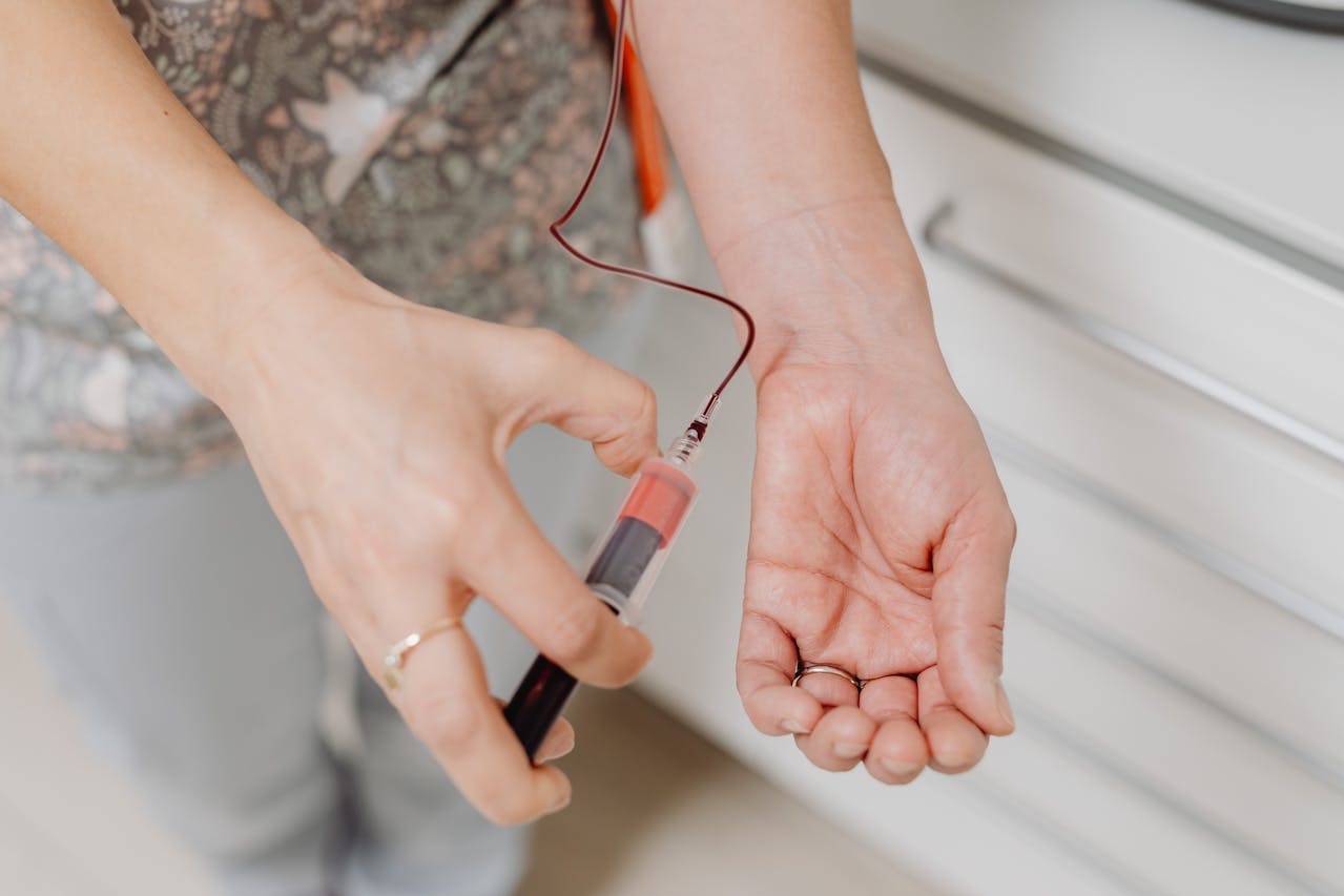Medical professional drawing blood from a patient’s wrist for liver function testing.