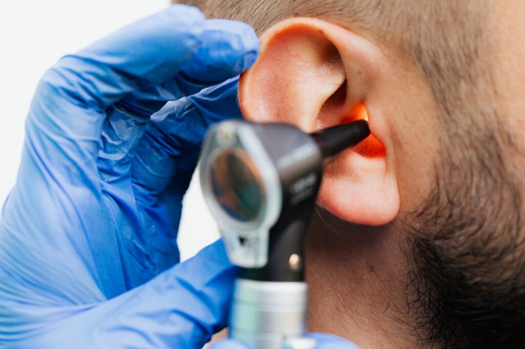 Close-up view of an ENT specialist examining a patient's ear using an otoscope.