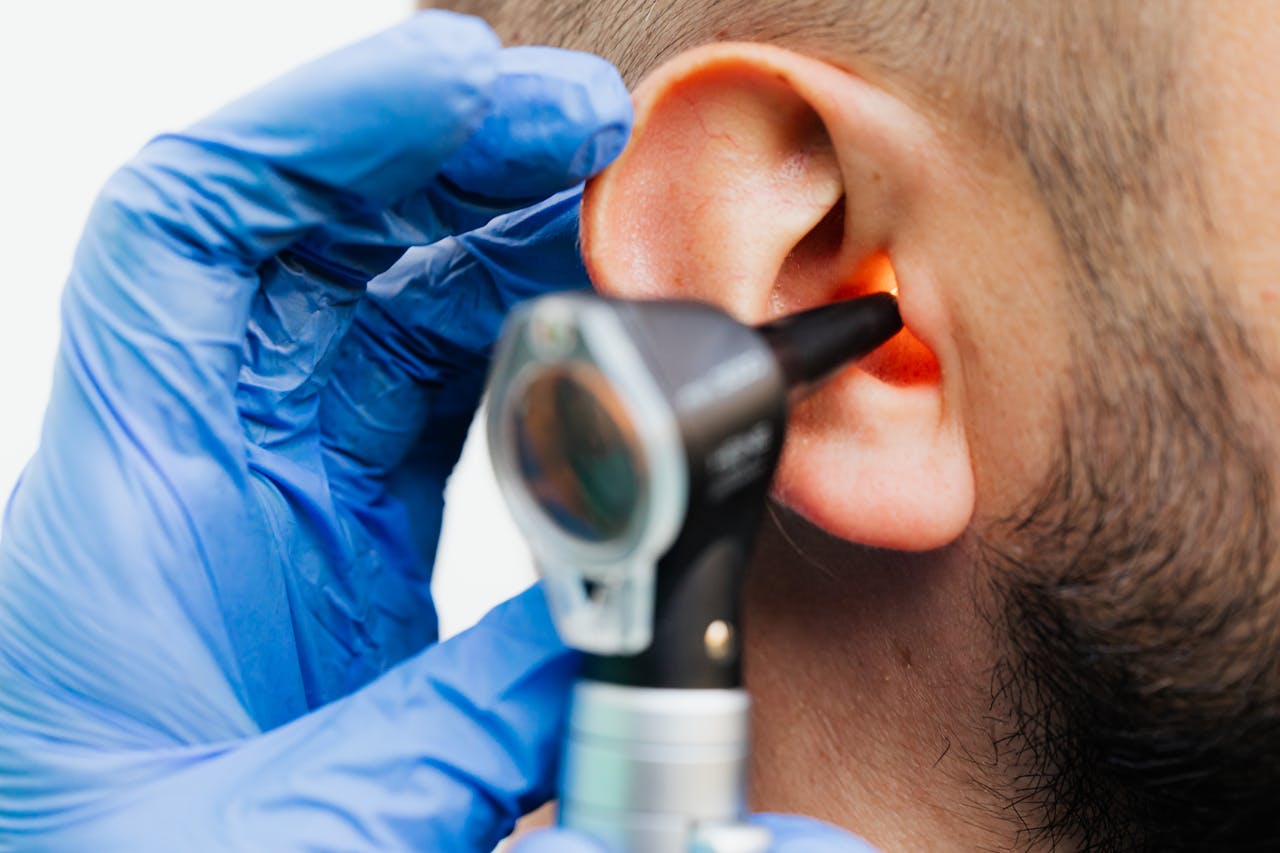 Close-up view of an ENT specialist examining a patient's ear using an otoscope.