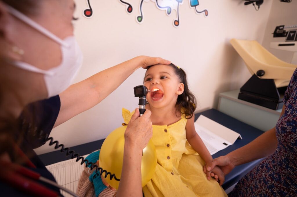 Paediatrician examining a child’s throat during a routine check-up in a child-friendly clinic