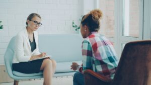 Psychiatrist listening to a patient and taking notes during a mental health consultation.