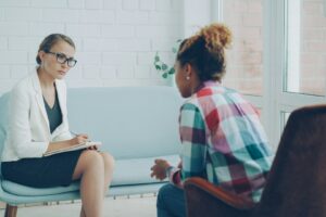 Psychiatrist listening to a patient and taking notes during a mental health consultation.